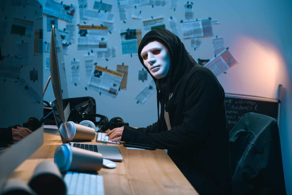 hacker in mask developing malware at his workplace 397G6TT 1 1